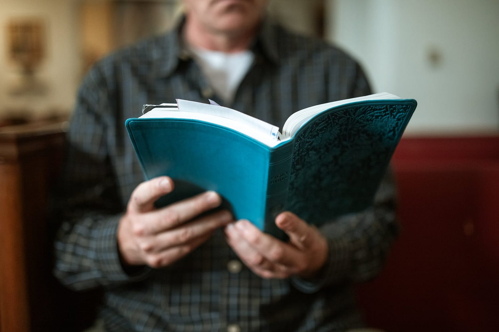 man in black and white plaid suit holding blue book