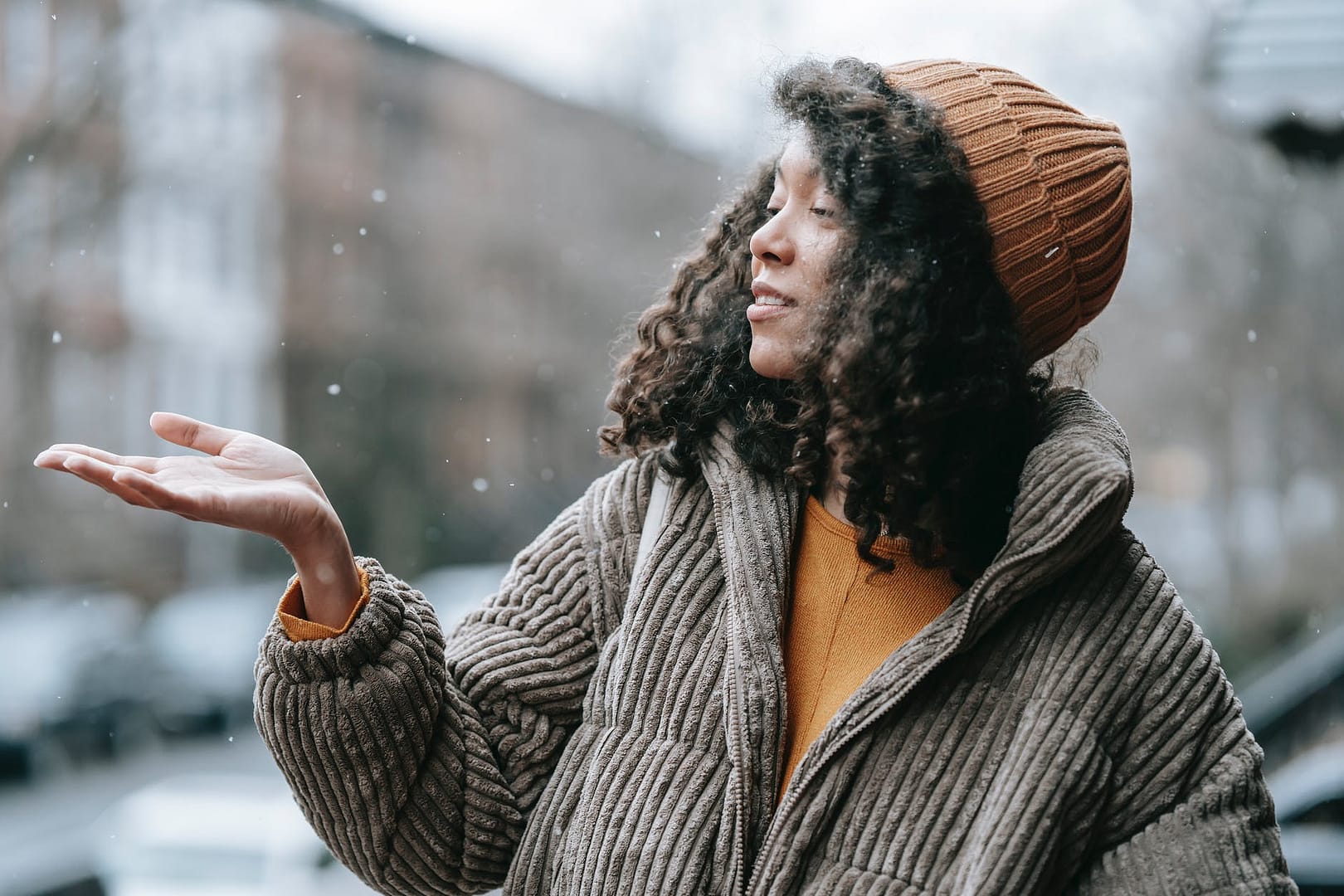 black woman catching snow in winter city