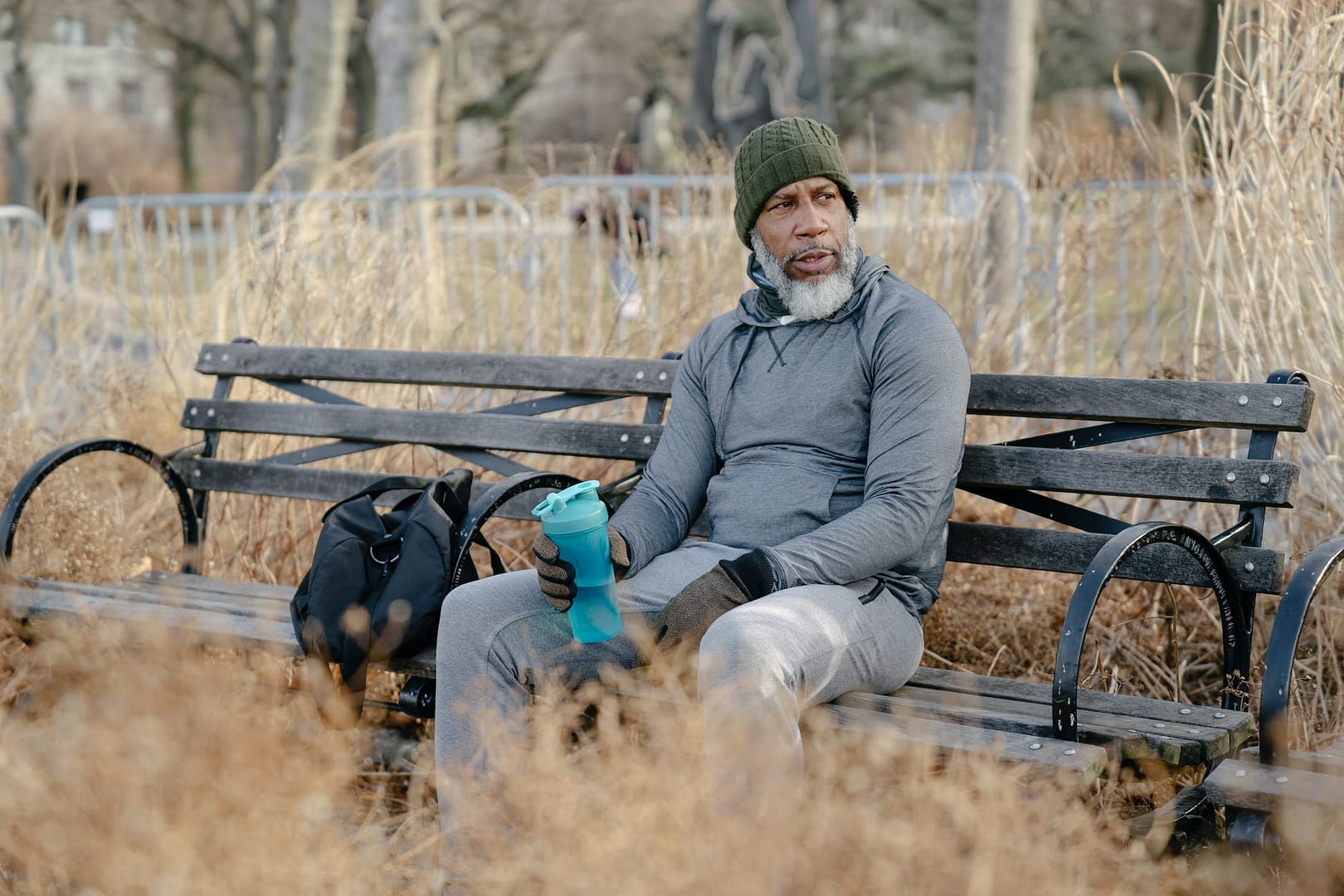 serious old black man in sportswear resting on bench