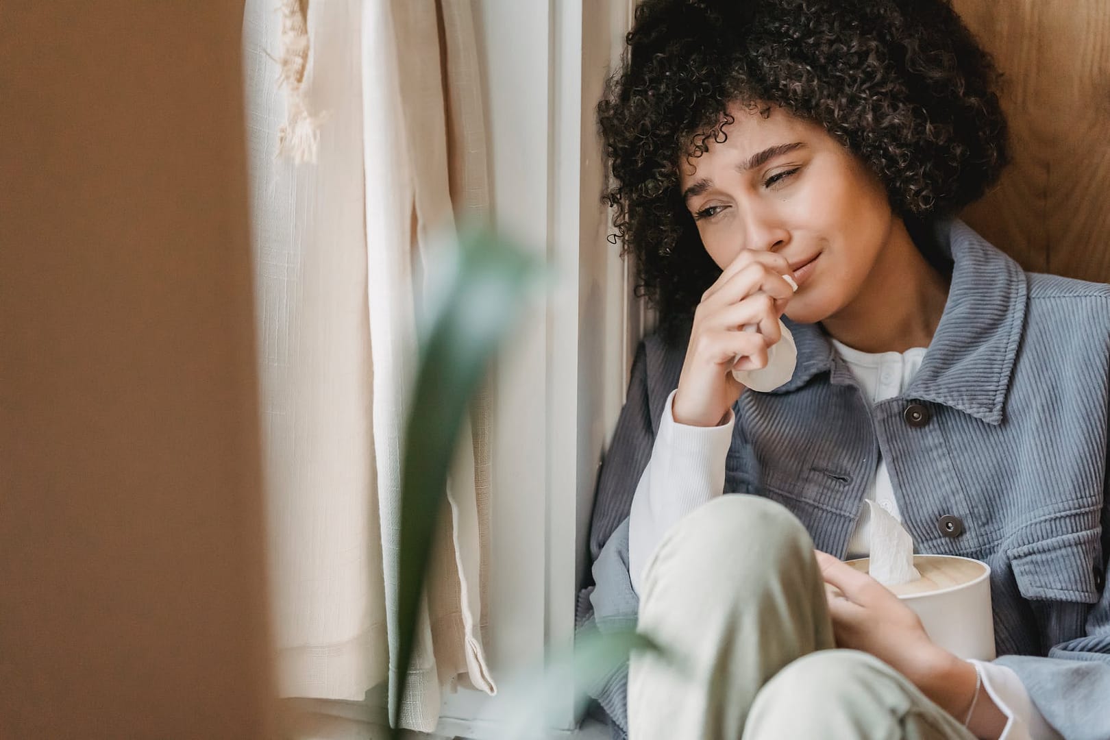 sorrowing black woman crying sitting on windowsill