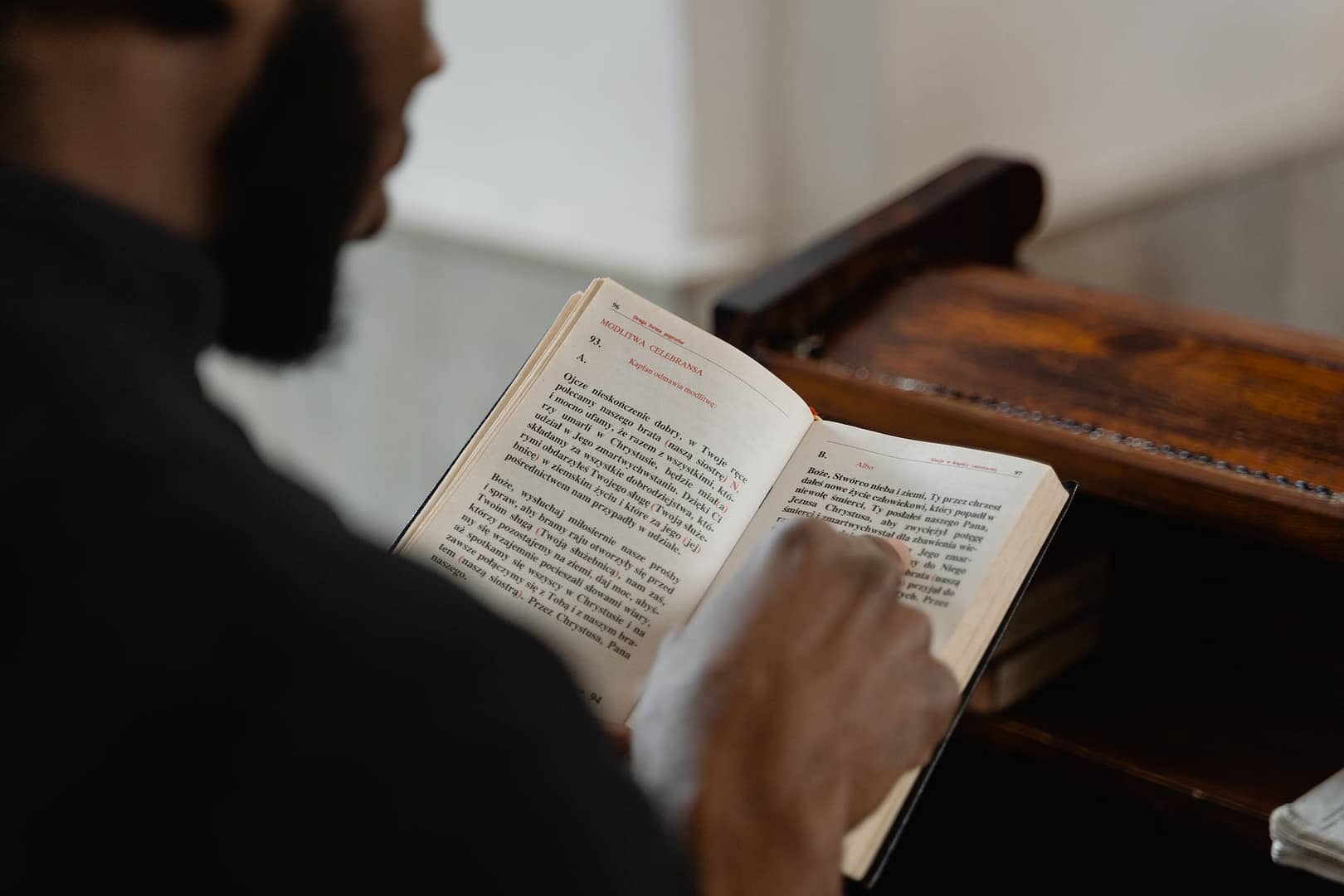 man in black robe reading the holy bible