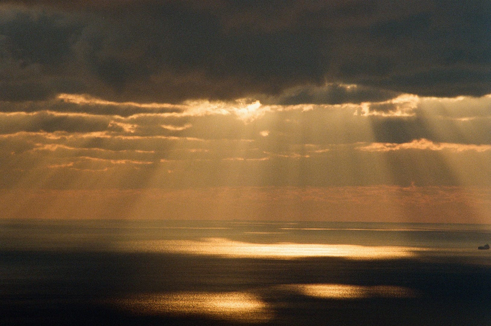 dramatic view on sea illuminated by sunlight coming from behind storm clouds