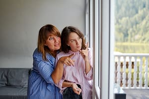 women carefully looking out window together